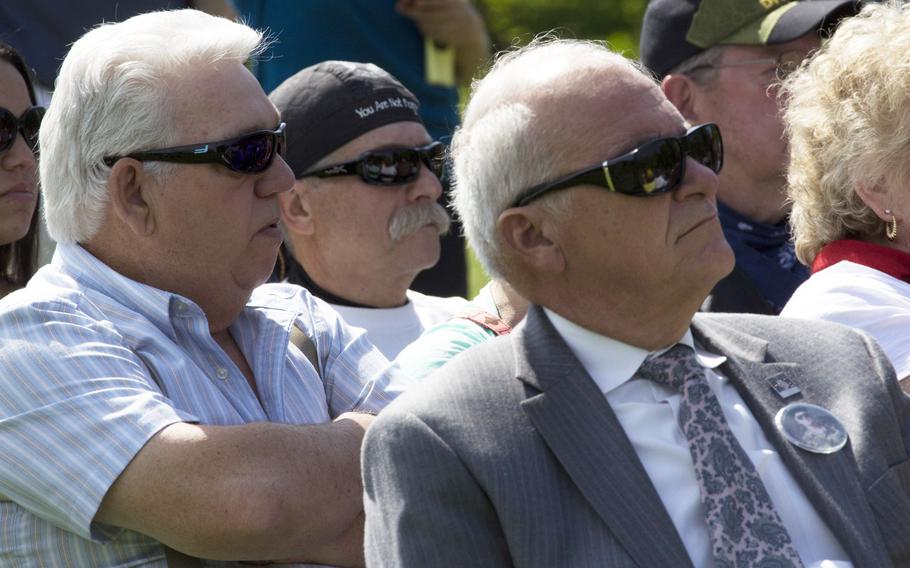 Friends and relatives listen to a speaker during a ceremony at the Vietnam Veterans Memorial in Washington, D.C. on May 11, 2014 marking the addition of 13 names to the Wall and the change of status of eight others.