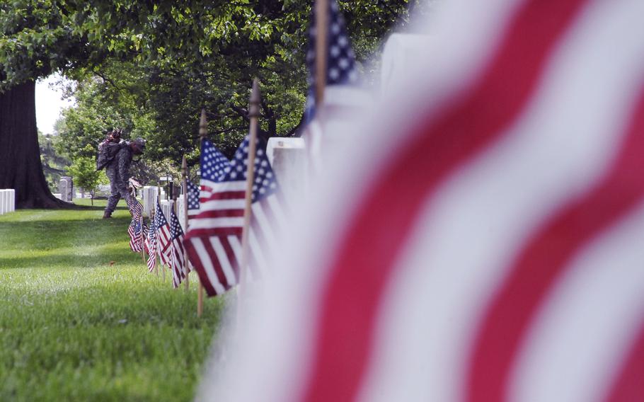 Staff Sgt. Francisco Armenta plants flags at graves at Arlington National Cemetery on May 22, 2014 as part of a "Flags In" ceremony to honor fallen troops for Memorial Day.