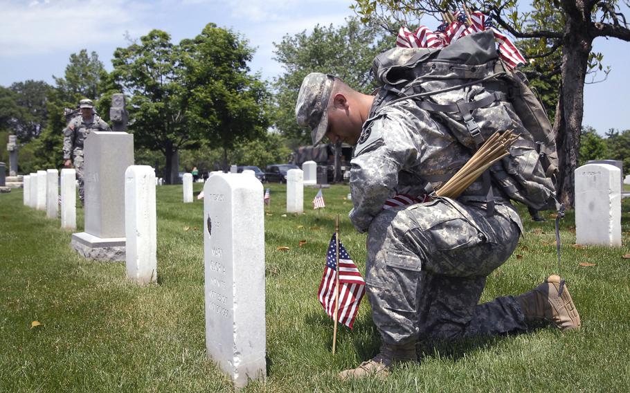 A soldier plants flags at graves at Arlington National Cemetery on May 22, 2014 as part of a "Flags In" ceremony to honor fallen troops for Memorial Day.