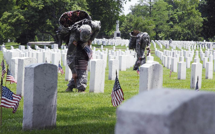 Soldiers plant flags at graves at Arlington National Cemetery on May 22, 2014 as part of a "Flags In" ceremony to honor fallen troops for Memorial Day. 