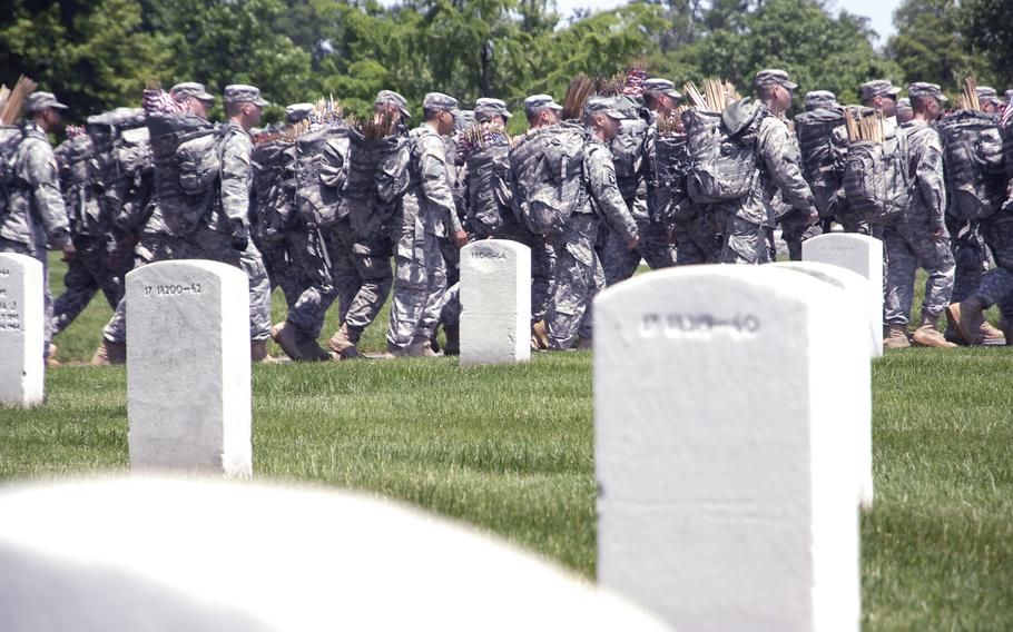 Soldiers head out to plant flags at graves at a "Flags In" ceremony at Arlington National Cemetery on May 22, 2014, to honor fallen troops for Memorial Day.