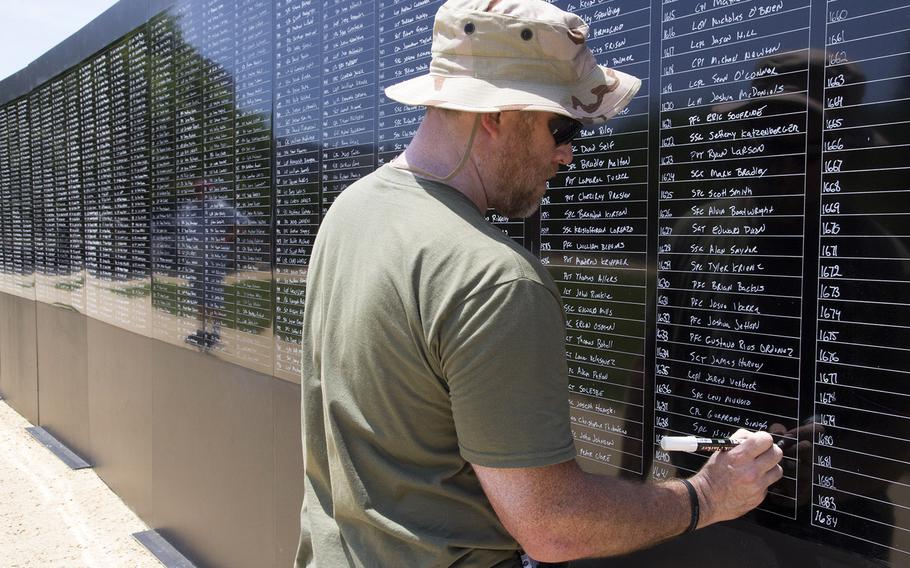 Memory champion Ron White writes the names of all the American servicemembers killed in Afghanistan on a wall, from memory, on the National Mall Before the National Memorial Day Parade in Washington, D.C., May 26, 2014.