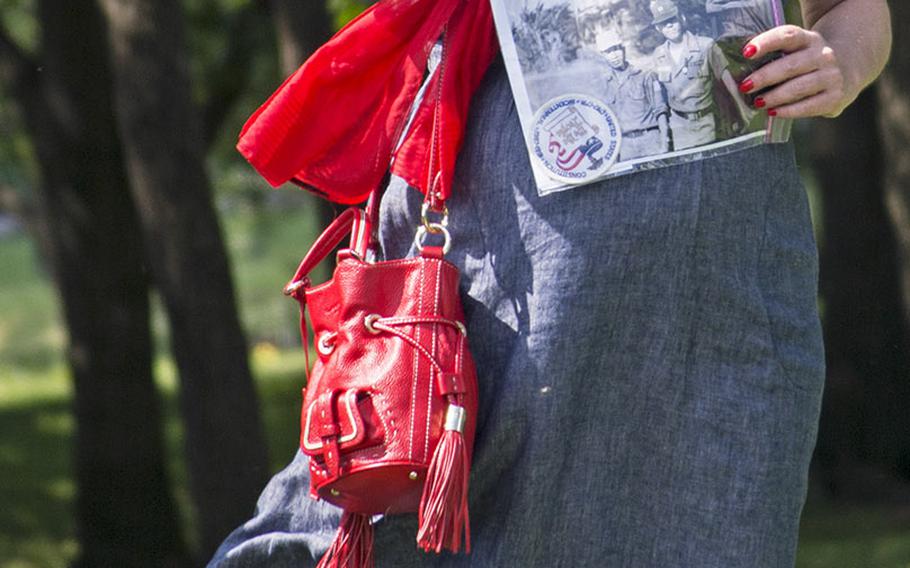 A woman holds onto her hat on a windy Saturday during the In Memory Day observance on June 14, 2014. She was waiting her turn to read the name of a Vietnam veteran whose picture she was holding. 