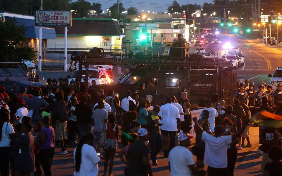 Protesters stand off with police in front of the QuikTrip on W. Ferguson Ave. on Wednesday, Aug. 13, 2014, in Ferguson, Mo. The protest was peaceful and the police allowed it until a couple objects were thrown at the police. The police then used tear gas and flashbangs to clear the area.