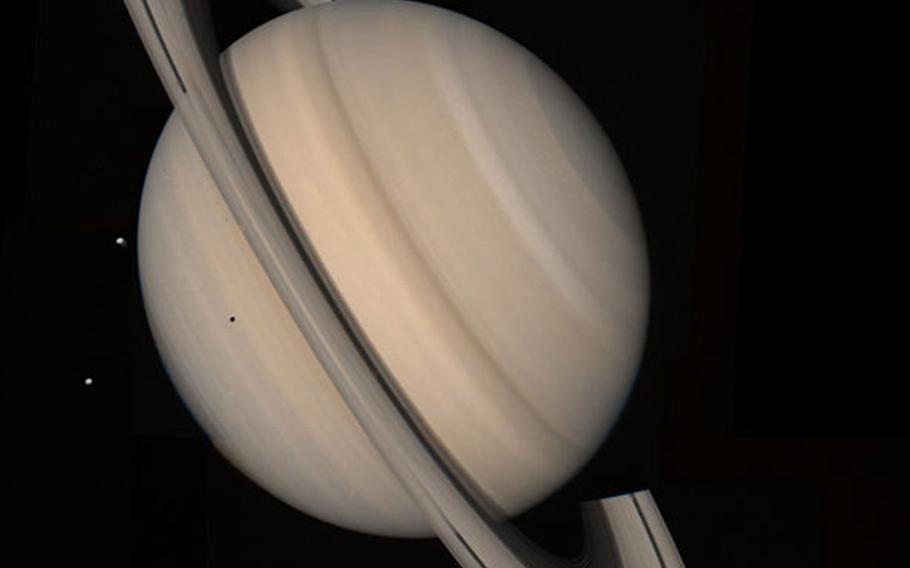 Voyager 2 snapped this true color image of Saturn from a distance of 13 million miles on Aug. 4, 1981. Three of the planet's moons are seen to the left, they are Tethys, closest, Dione and Rhea.
