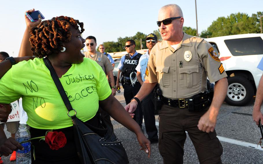 A protester yells at police after her friend was arrested Tuesday in Ferguson, Mo. Protests over the shooting of a black teen by a white police officer have escalated into riots, and the Missouri governor recently made the controversial decision to call up National Guard troops to assist law enforcement. 