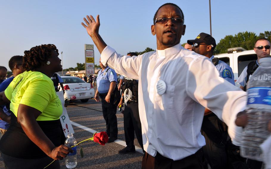 A man calls for calm Tuesday in Ferguson, Mo., as protesters square off with police. Protests over the shooting of a black teen by a white police officer have escalated into riots, and the Missouri governor recently made the controversial decision to call up National Guard troops to assist law enforcement.