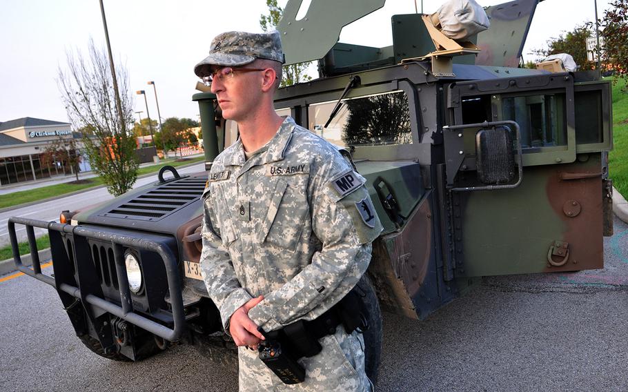 A Missouri National Guard soldier watches the entrance to a mall parking lot that has turned into a police and military command center in Ferguson, Mo. Protests over the shooting of a black teen by a white police officer have escalated into riots in the St. Louis suburb, and the Missouri governor recently made the controversial decision to call up National Guard troops to assist law enforcement.