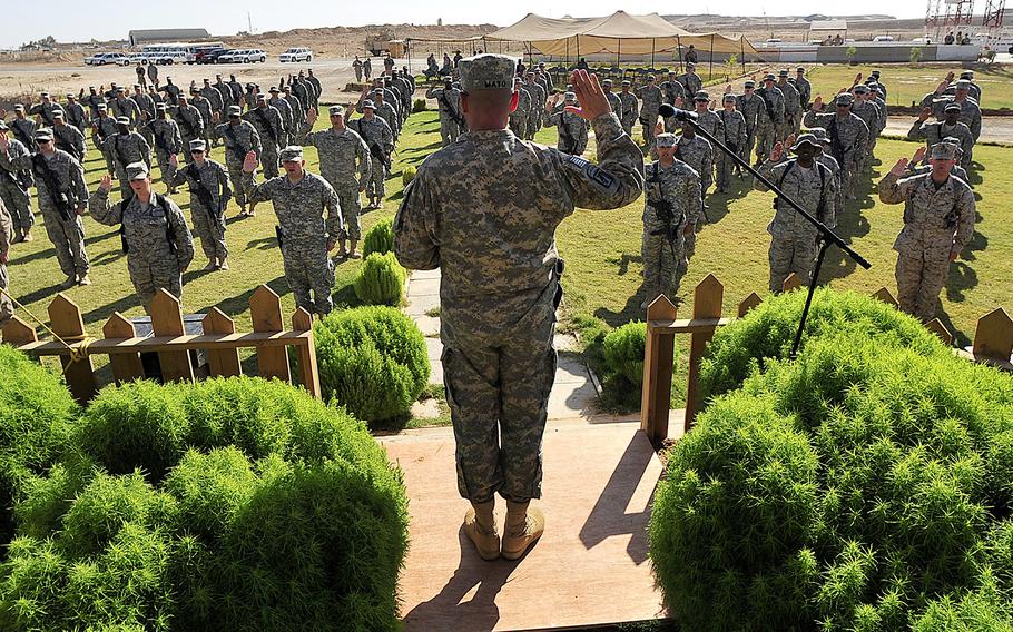 With hands raised, 126 U.S. servicemembers rehearse prior to a mass re-enlistment ceremony at Al Asad Air Base, Iraq, Oct. 5, 2011.