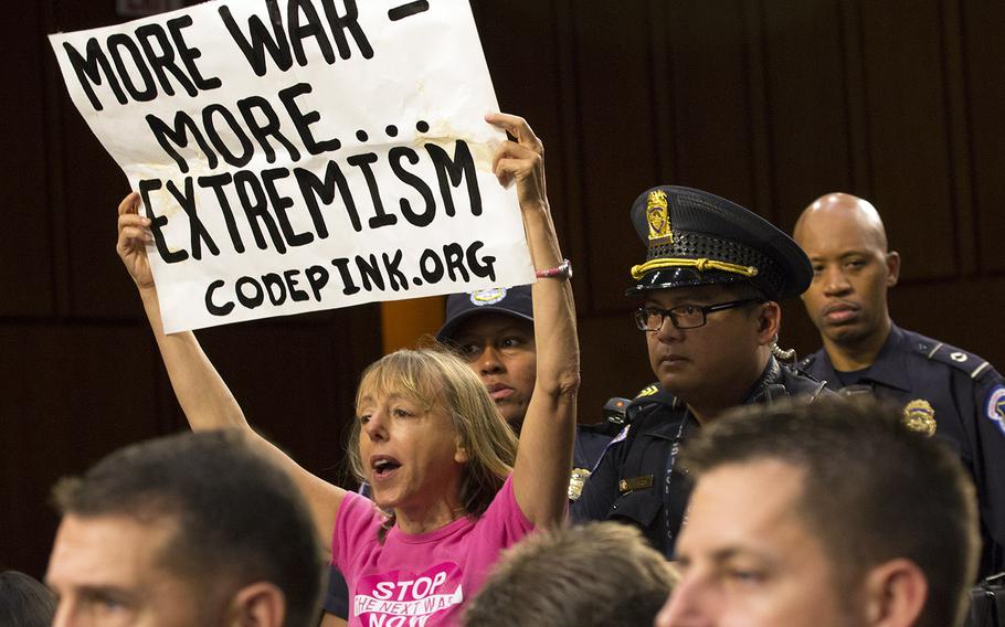 U.S. Capitol police move in on a Code Pink protester who began shouting during a Senate Armed Forces Committee hearing, Sept. 16, 2014.