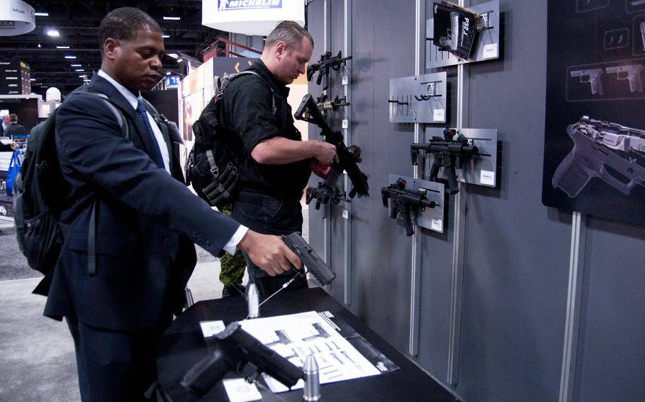 AUSA 2014 attendees check out guns at the SIG Sauer booth in Washington, D.C. on Oct. 15, 2014.