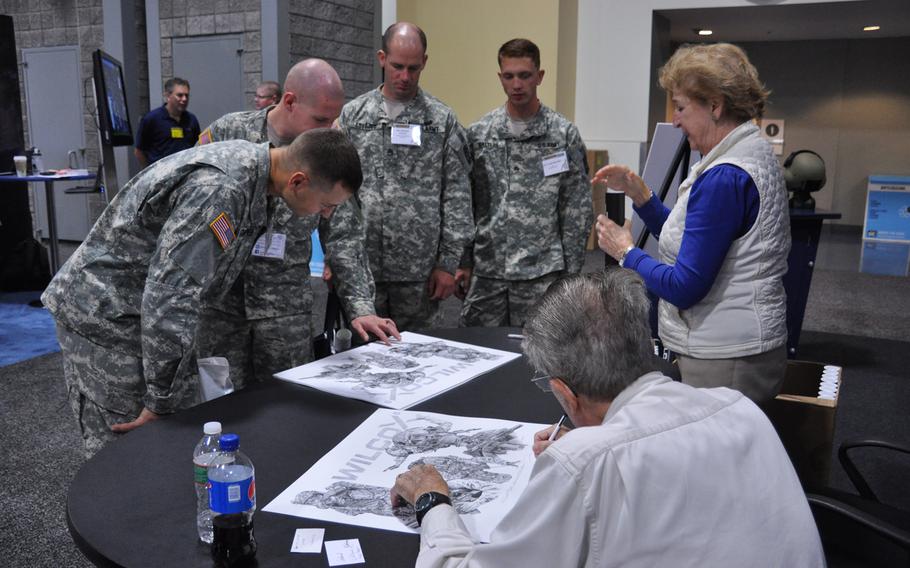An artist autographs posters for soldiers at AUSA's annual expo in Washington, D.C. on Oct. 15, 2014. 