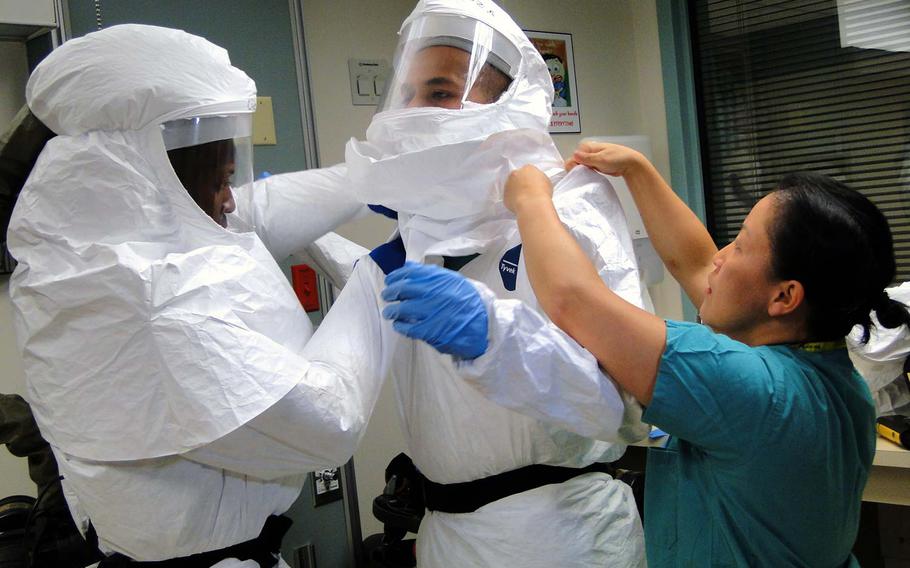 Members of the Defense Department's medical support team formed to assist civilian hospitals with Ebola patients, if needed, practice putting on and taking off protective suits Friday, Oct. 24, 2014, at San Antonio Military Medical Center in Texas.