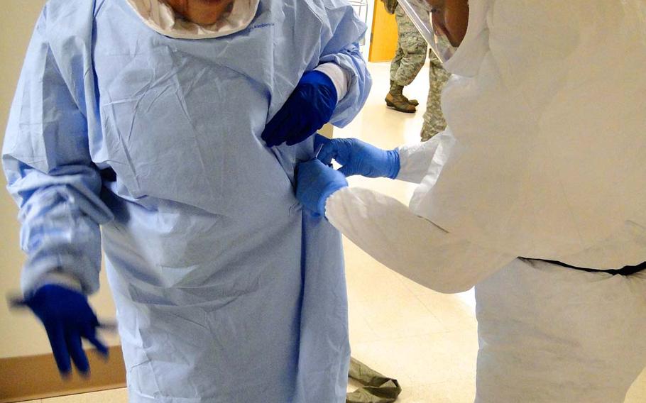 Members of the Defense Department's medical support team formed to assist civilian hospitals with Ebola patients, if needed, practice putting on and taking off protective suits Friday, Oct. 24, 2014, at San Antonio Military Medical Center in Texas. Officials said the suits take at least 15 minutes to put on or take off properly.
