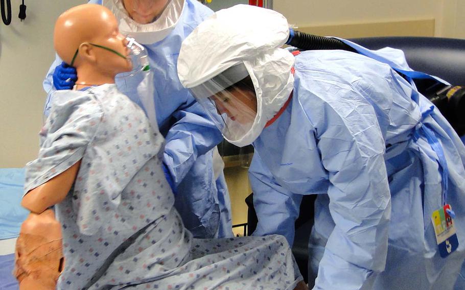 Members of a 30-person military team training to be a rapid-response team for treating Ebola patients in the U.S. practice transferring a patient from a bed to a chair while wearing protective suits Friday, Oct. 24, 2014, at San Antonio Military Medical Center in Texas.