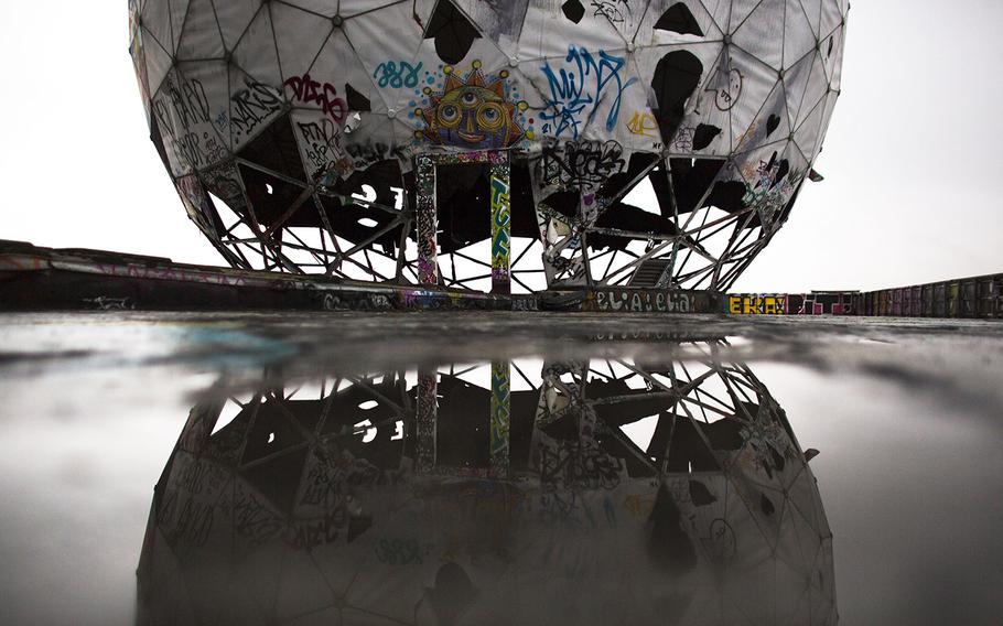 In this Oct. 16, 2014 photo, the ruin of a vandalized, golf ball-shaped cover for antennas of the abandoned former listening station of the United States National Security Agency, at the Teufelsberg (Devil's Mountain) is reflected in a puddle in Berlin. The listening station, which was active until the early '90s, is now used by graffiti artists and can be visited only with guided tours.