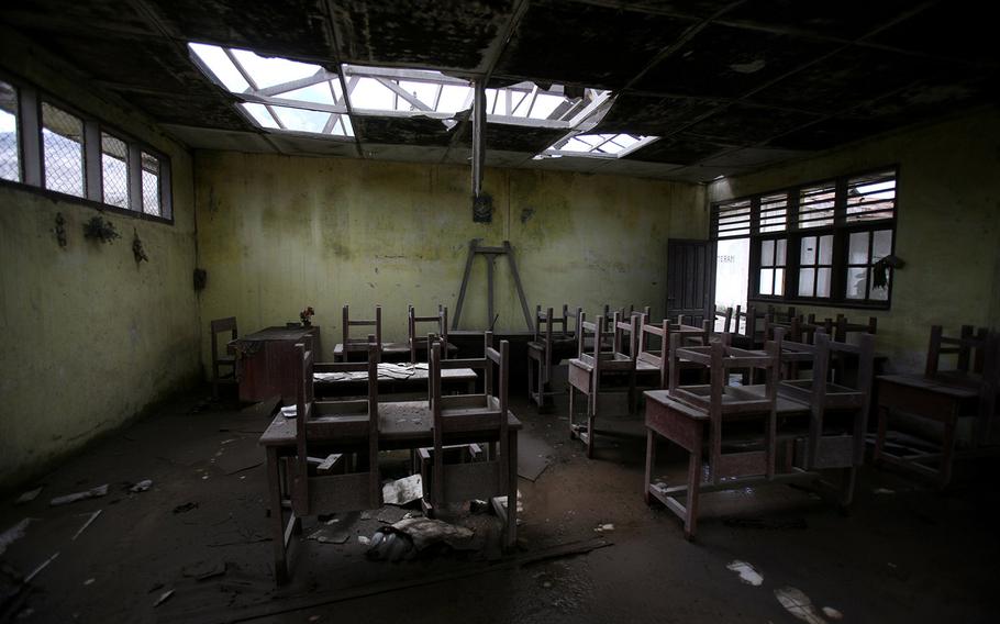 In this Oct 17, 2014, photo, chairs rest on tables in an empty classroom at an elementary school in the abandoned village of Simacem, North Sumatra, Indonesia. The village was abandoned after its people were evacuated following the eruption of Mount Sinabung. 