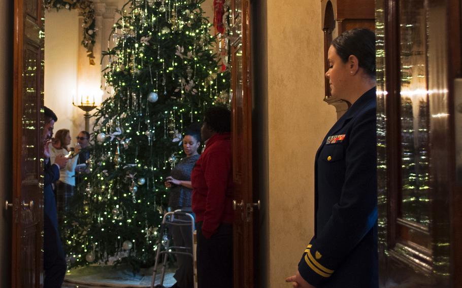 One of the trees at the White House doors reflects off an Eat Room door while a servicemember watches visitors at the White House on Dec. 3, 2014.
