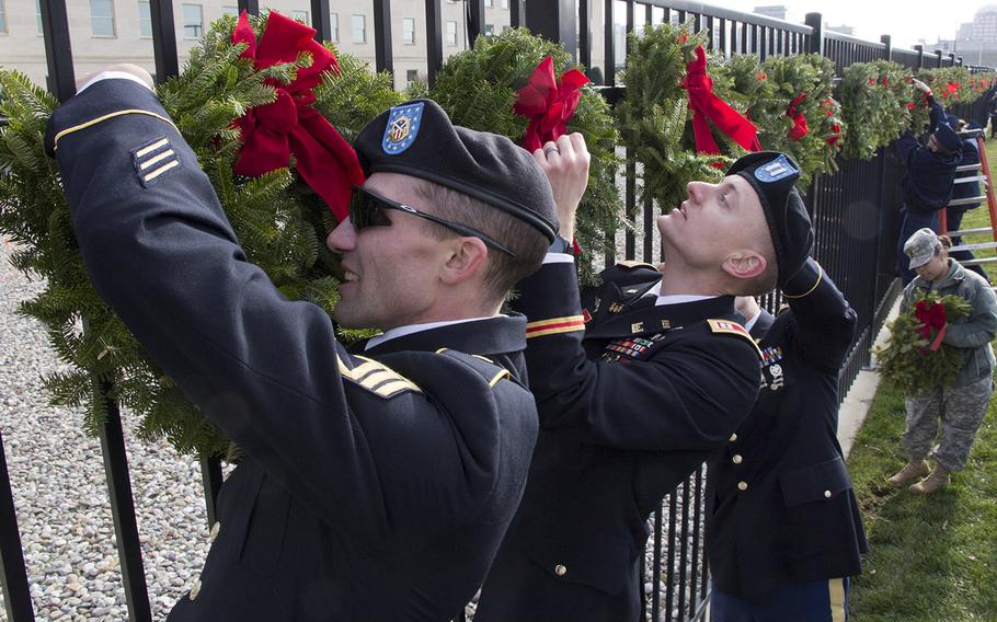 Servicemembers join civilian volunteers in placing wreaths on a fence at the National 9/11 Pentagon Memorial in Arlington, Va., as part of Wreaths Across America  Dec. 12, 2014.
