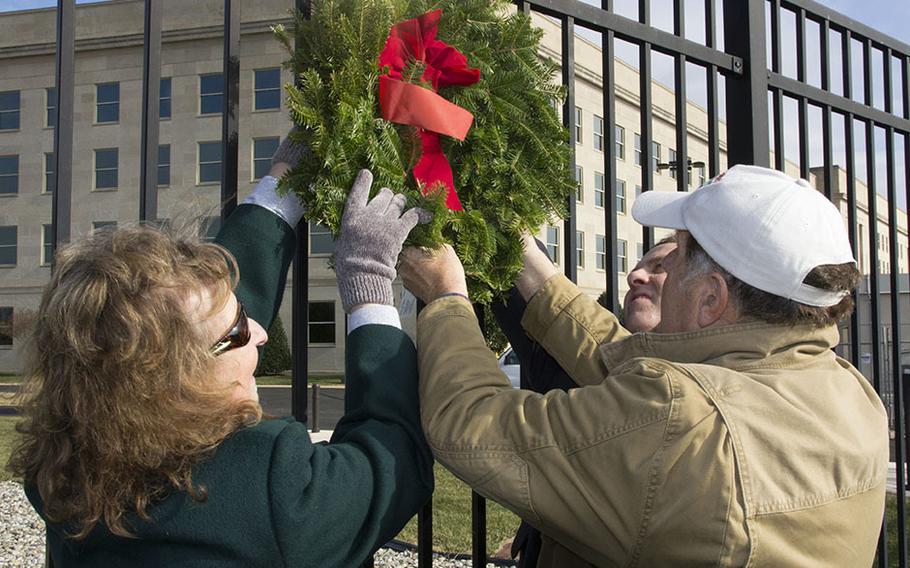 Retired Army civilian Kathy Dillaber, who survived the 9/11 attack on the Pentagon, joins Wreaths Across America founder Morrill Worcester, right, and Pentagon Memorial Fund President Jim Laychak, background, in placing the ceremonial first wreath at the Pentagon Memorial, Dec. 12, 2014. Volunteers placed 184 wreaths in honor of those who died in the attack, including Dillaber's sister, Patty Mickley.