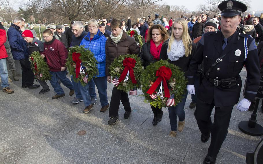 Portland, maine police officer Kevin Haley, right, and members of his family walk up to place wreaths at the graves of President and Mrs. John F. Kennedy during Wreaths Across America at Arlington National Cemetery, Dec. 13, 2014.
