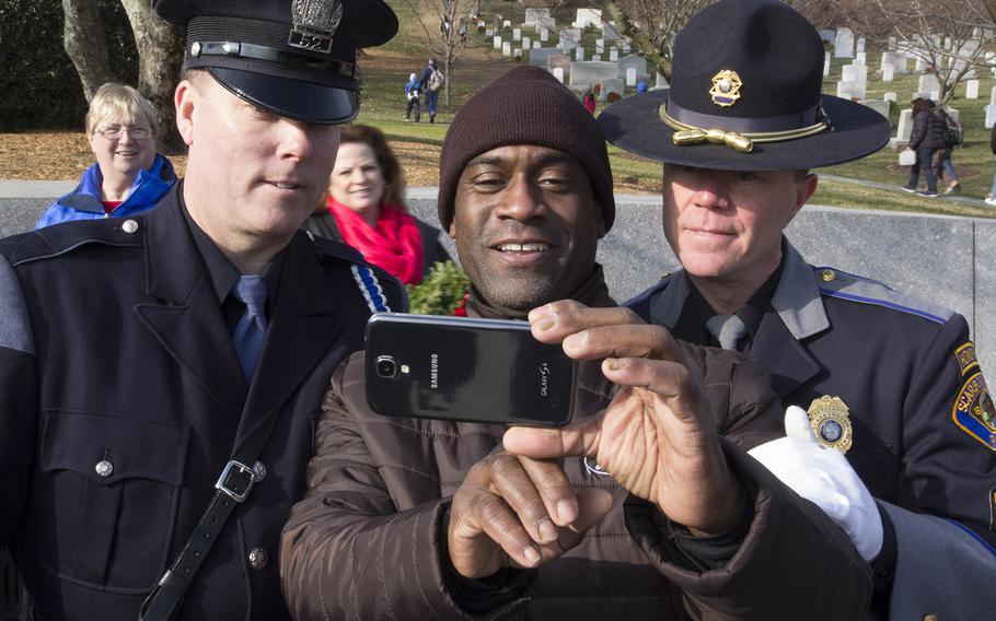 A visitor takes a selfie with Maine police officers Kevin Haley, left, and Steven Thibodeau during Wreaths Across America at Arlington National Cemetery, Dec. 13, 2014.
