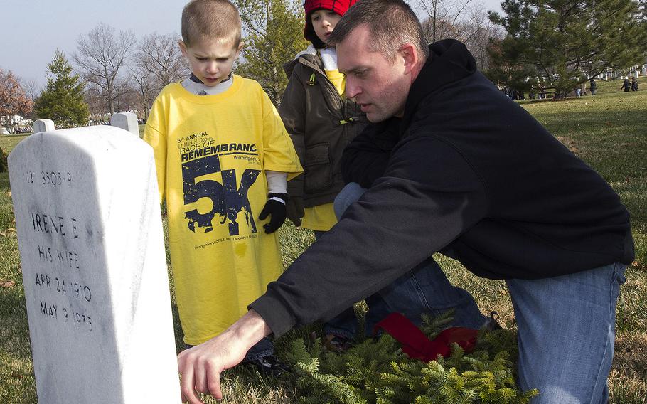 Navy Lt. Cmdr. Ryan Anderson tells his sons Connor, left, and Nathan about the veteran on whose Arlington National Cemetery grave they are about to place a wreath during the annual Wreaths Across America event, Dec. 13, 2014.