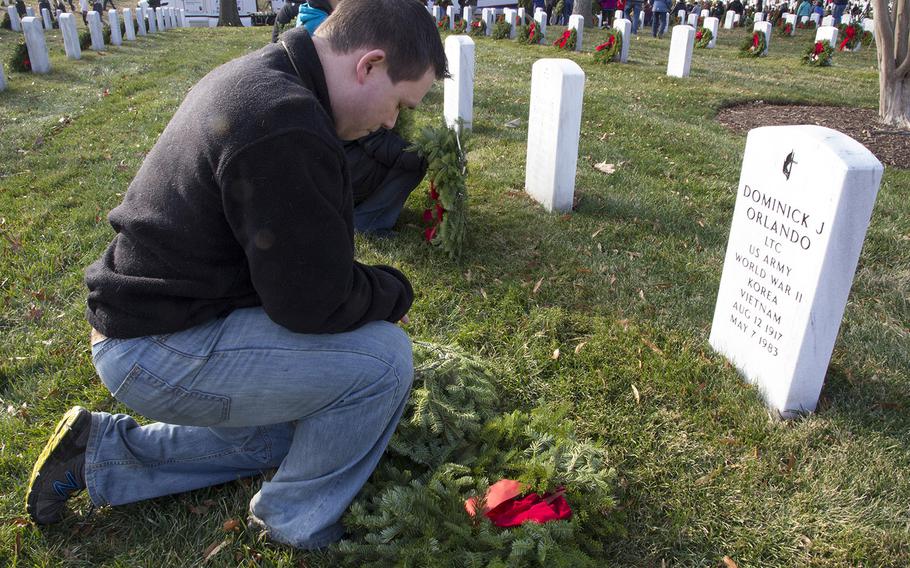 Dennis Coster Jr. says a prayer before placing a wreath on a grave during Wreaths Across America at Arlington National Cemetery, Dec. 13, 2014.