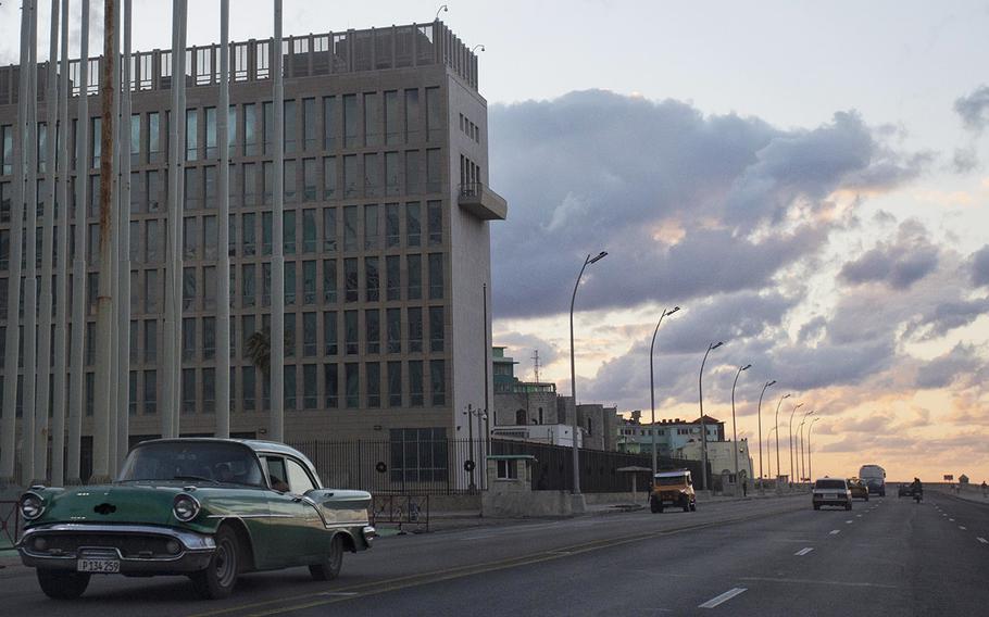 This Dec. 17, 2014 file photo shows a classic American car driving past the U.S. Interests Section building in Havana, Cuba.