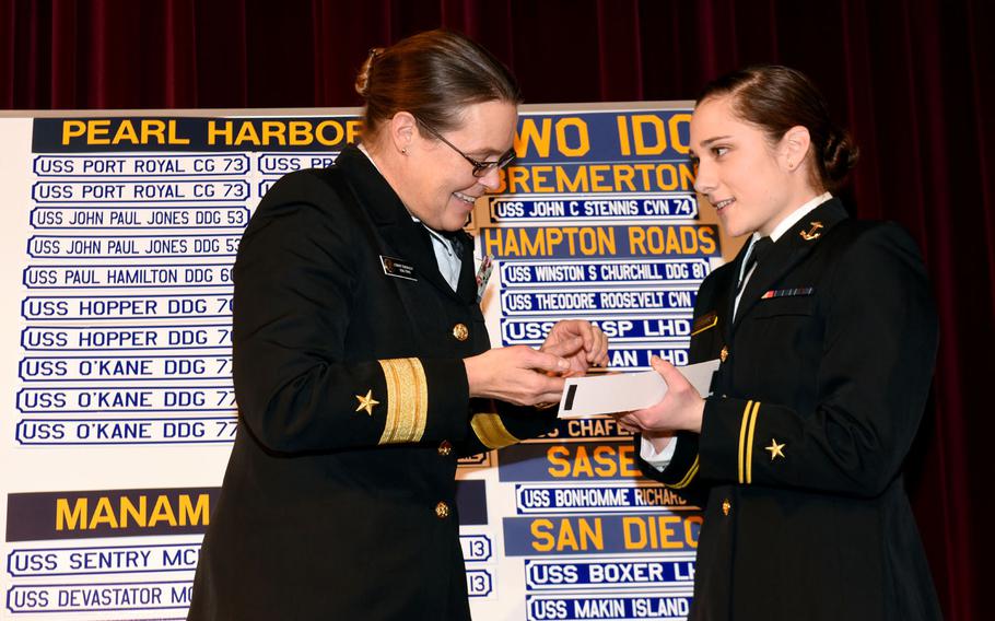 Rear Adm. Cynthia M. Thebaud, commander of Expeditionary Strike Group 2, presents her Surface Warfare Officer pin to U.S. Naval Academy Midshipman 1st Class Lily Van Steenberg during Ship Selection Night in Mahan Hall on Jan. 29, 2015. Ship Selection is the culmination of the service assignment process for Naval Academy midshipmen assigned to serve as Navy Surface Warfare Officers. Upon reporting to their first ship after graduation and commissioning, they will be in charge of any number of shipboard operations and activities while at sea.