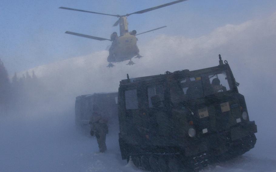 A CH-47 helicopter hovers over a Small Unit Support Vehicle at the Black Rapids Training Site, Alaska, on Feb. 9, 2015.