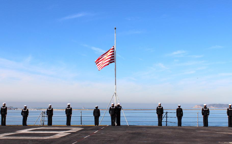 Sailors hoist a flag on the USS Makin Island as the ship docks at Naval Base San Diego on Wednesday morning. The crew was returning from a seven-month deployment.