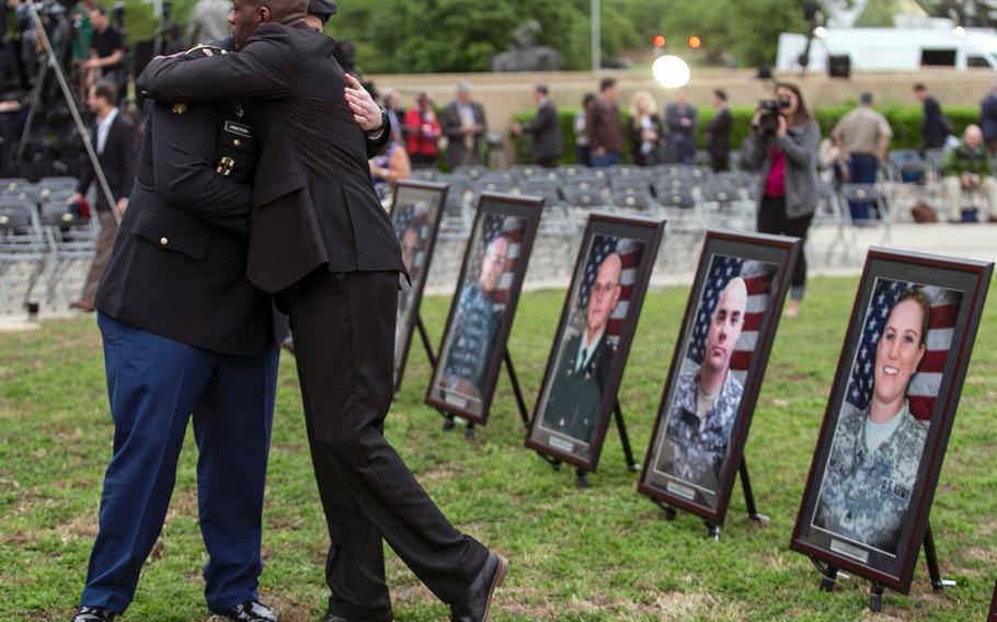 Purple Heart recipients Pfc. James Armstrong, left, and Chief Warrant Officer 2 Christopher Royal hug as they look at pictures of co-workers who were killed in the 2009 Fort Hood shooting, prior to a ceremony on April 10, 2015, at Fort Hood, Texas.