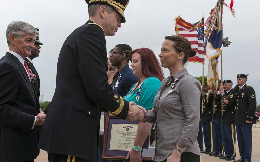 Secretary of the Army, John McHugh, far left, looks on as Lt. Gen. Sean B. MacFarland, center, shakes the hand of Defense of Freedom Medal recipient Kimberly Munley, who was wounded in the 2009 Fort Hood Shooting.