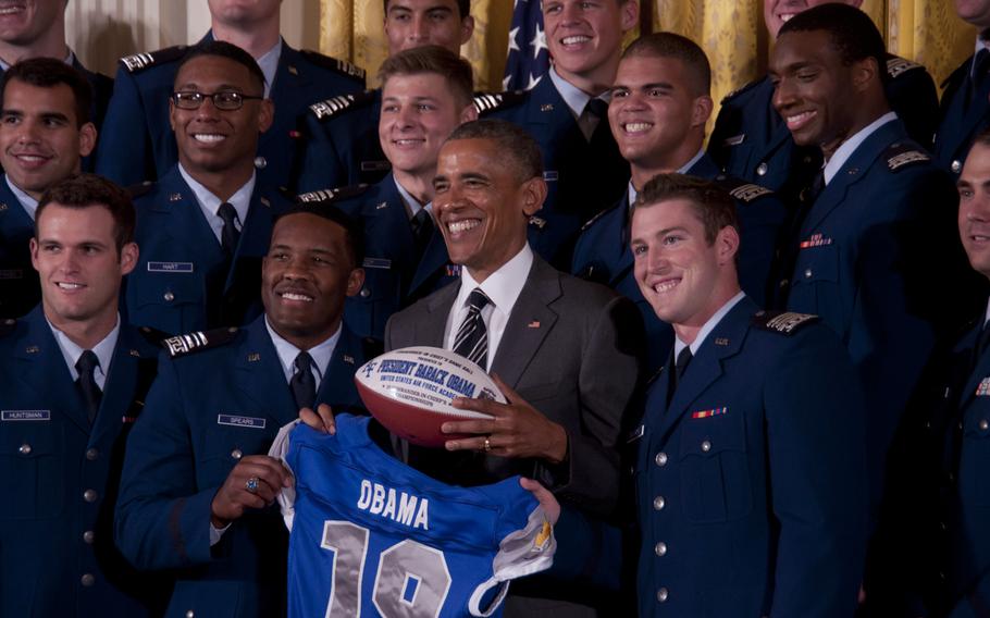  President Barack Obama gets a jersey and football from the United States Air Force Academy football team after presenting them with the Commander-in-Chief's Trophy at the White House on May 7, 2015. The Air Force Falcons beat the Army team 23-6 in November to win the trophy. Falcons quarterback Kale Pearson (right), presented Obama with a No. 19 jersey, and defensive back Christian Spears (left) gave the president a game ball. 