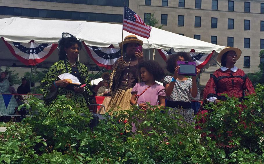 Reenactors watch from the sidewalk while troops march by in Washington, D.C., on Sunday, May 17, 2015.