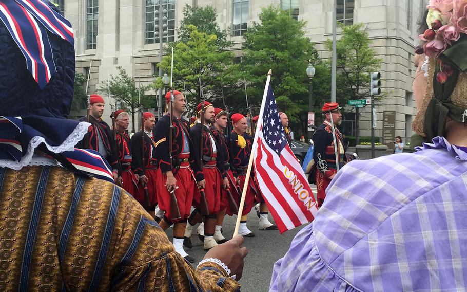Reenactors watch from the sidewalk while troops march by in Washington, D.C., on Sunday, May 17, 2015.