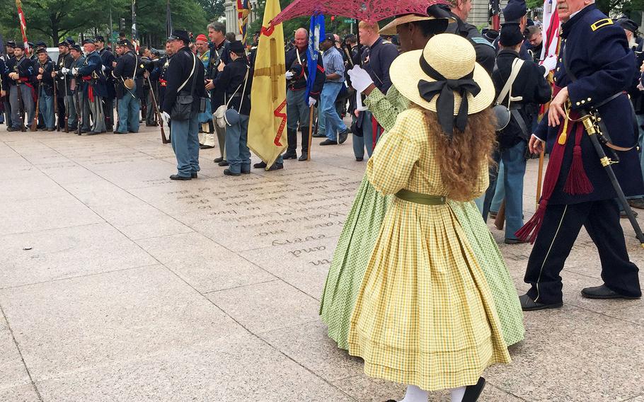 A woman walks a child past reenactors in Washington, D.C., on Sunday, May 17, 2015, following the 150th anniversary of the Grand Review Parade.