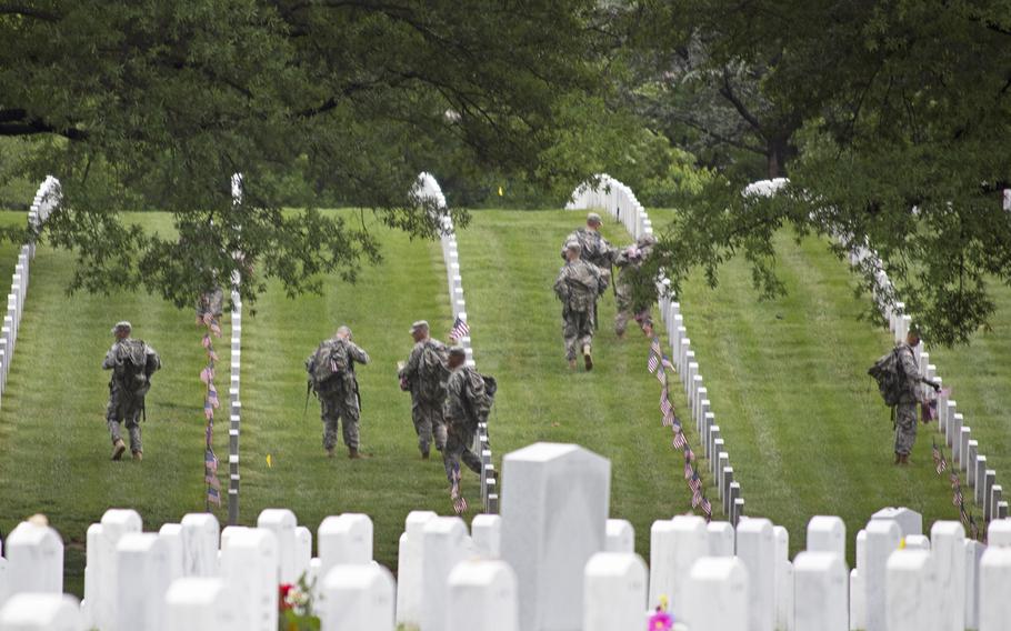Members of The Old Guard place American flags at headstones at Arlington National Cemetery during Flags-In on May 21, 2015. 