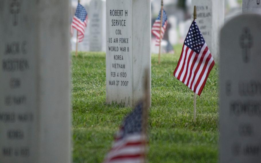 A rose rests near an American flag at a headstone at Arlington National Cemetery Thursday, May 21, 2015, during Flags-In. Every headstone received an American flag by the Old Guard.