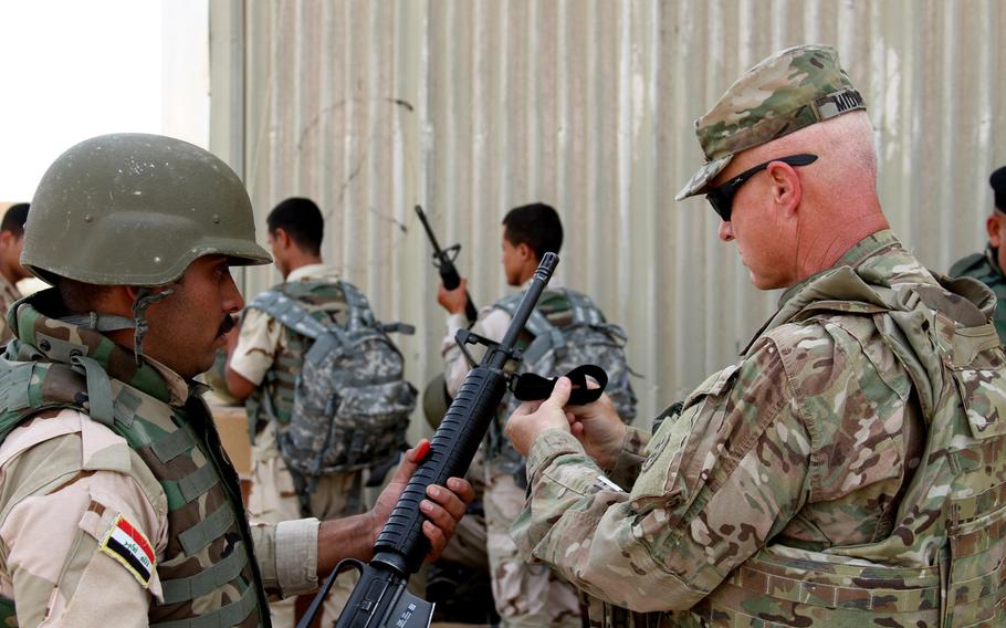U.S. Army Col. Michael Midkiff (right), 310th Sustainment Command (Expeditionary) and officer in charge of the 1st Sustainment Command (Theater) Logistics Advise and Assist Team from Fort Bragg, N.C., helps an Iraqi soldier with a sling for an M16A2 rifle received as part of the fielding of combat brigade sets supplied to Iraqi Security Forces from Combined Joint Task Force Operation Inherent Resolve May 26, 2015, at Camp Taji, Iraq. 