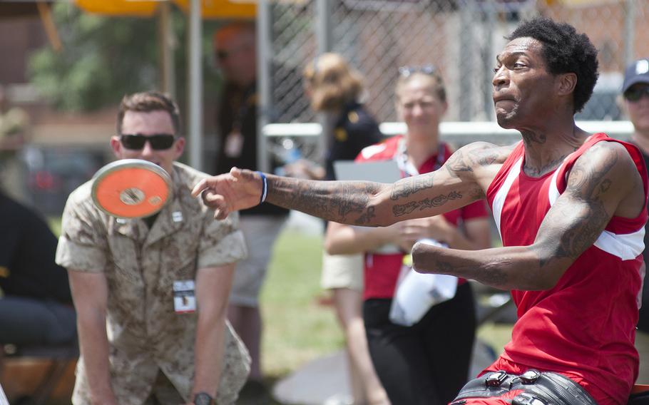 Anthony McDaniel competes in a discus event Tuesday June 23, 2015, during the Warrior Games held at Quantico Marine Base, Virginia. Watching from the sidelines is Marine Capt. James Ferguson, who was present in Afghanistan in 2010 when McDaniel suffered major injuries from an IED blast losing both legs and his lower left arm. McDaniel won seven gold medals at the Warrior Games last year.
