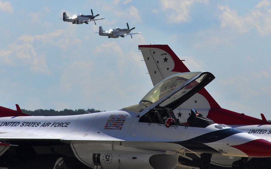 United States Air Force Thunderbirds planes are prepared for their demonstration at the 2015 Joint Base Andrews Air Show as two P-51 Mustangs fly in the distance.