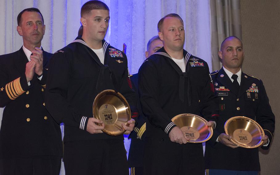 Chief of Naval Operations Adm. John Richardson claps as three of the five Angels of the Battlefield honorees pose with their award. From left to right, they are: Navy Petty Officer 1st Class Wayne Papalski, Petty Officer 1st Class Joshua Van Horn and Army Sgt. 1st Class Adam Morelli.