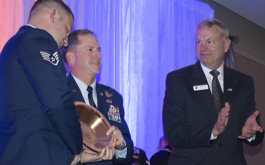 Air Force Staff Sgt. Christopher Dixon receives an award from U.S. Air Force Gen. David Goldfein during the Angels of the Battlefield Gala in Washington, D.C., on Nov. 4, 2015, as CEO and President of the Armed Services YMCA Bill French looks on. 