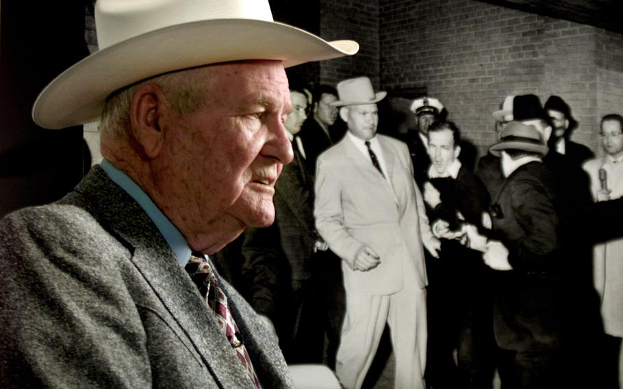 In a 2003 file photo, former Dallas Police Department Detective Jim Leavelle poses next to the famous photo of himself with Lee Harvey Oswald at the moment when Oswald was shot by Jack Ruby.