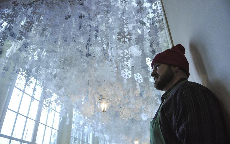 Hand-cut snowflakes fill the ceiling of a hallway above decorating volunteer Trevor Smith at the White House. First Lady Michelle Obama hosted a preview of holiday decorations for military families on Dec. 2, 2015.
