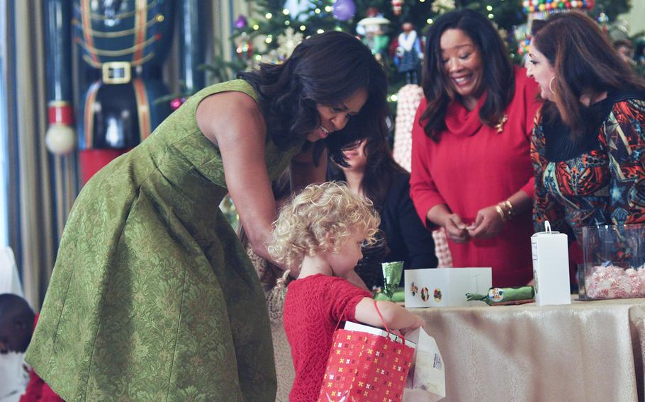 First Lady Michelle Obama helps Piper Charbonneau, a daughter of a Marine, load her bag with goodies at the White House on Dec. 2, 2015. Obama was hosting a preview of White House holiday decorations for military families.