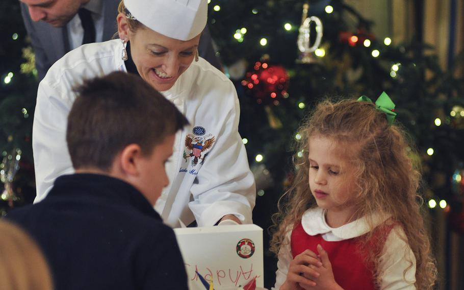White House Executive Pastry Chef Susan Morrison helps a military child decorate a cookie at the White House on Dec. 2, 2015. First Lady Michelle Obama was hosting a preview of the White House holiday decorations for military families.