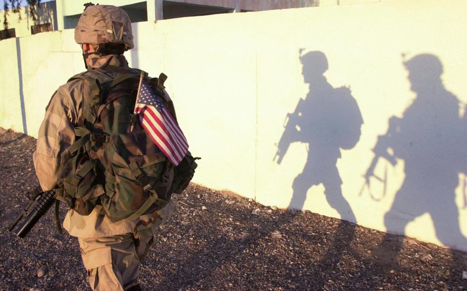 Spc. Javier Aguilar and another scout cast big shadows as they pass through Ad-Dawr, Iraq, in the late afternoon in February, 2005.